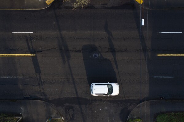 A car drives along César E. Chávez Boulevard past cracks in the road on Monday, March 17, 2025, in Portland, Ore. (AP Photo/Jenny Kane)