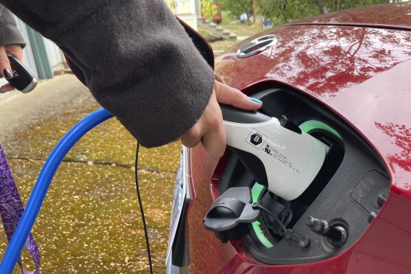 Rebecca DeWhitt charges her electric vehicle in the driveway of the Portland, Ore., home she rents on Sept. 30, 2022. (AP Photo/Gillian Flaccus, File)