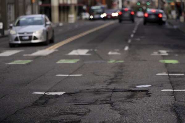 Cars drive along W Burnside Street as cracks are seen in the road on Thursday, Feb. 6, 2025, in Portland, Ore. (AP Photo/Jenny Kane)